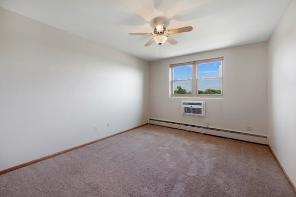 a room with white walls and a ceiling fan and a window