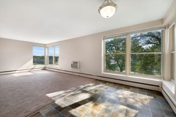 an empty living room with large windows and a rug