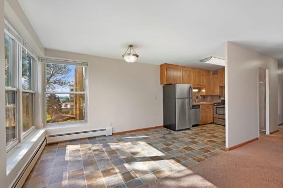 an empty living room with a large window and a kitchen