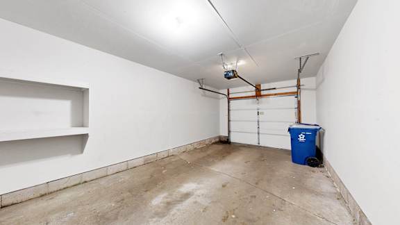 A white wall with a blue bin and a pipe.