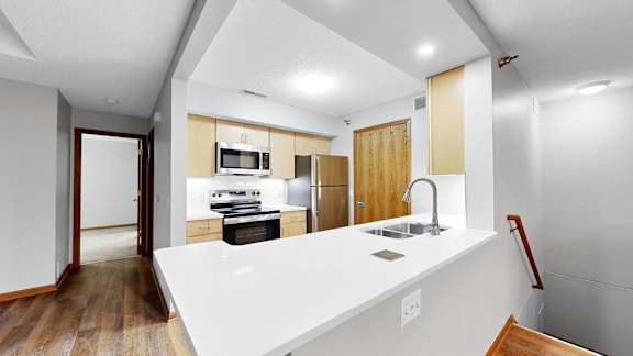A modern kitchen with a white countertop and wooden cabinets.