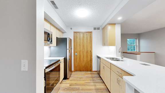 A kitchen with wooden floors and white countertops.