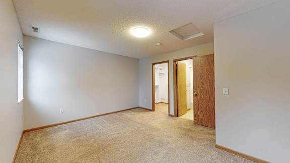 A room with a carpeted floor and a door on the right side.
