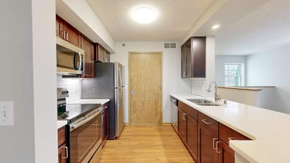 A kitchen with a black refrigerator and wooden floors.