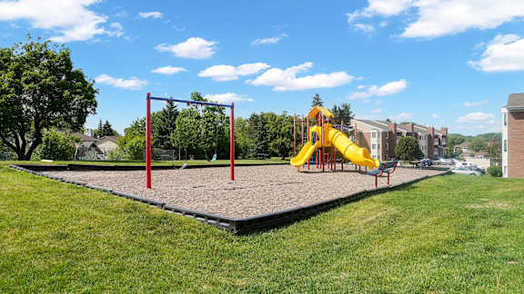 A playground with a red swing set and a yellow slide.