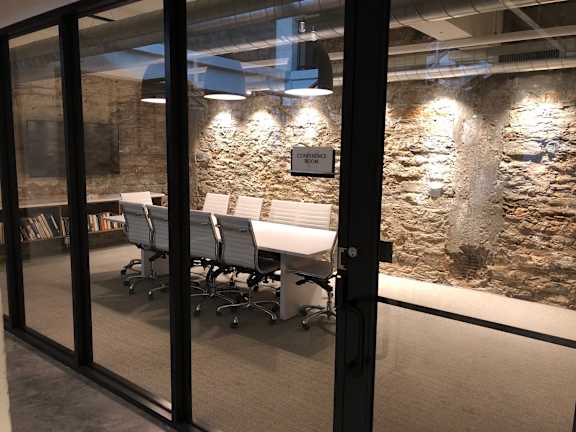 A conference room with a stone wall and glass doors.