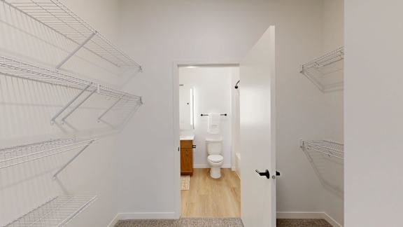 A white hallway with a doorway leading to a bathroom.