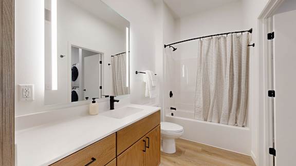 A white bathroom with a toilet, sink, and shower.