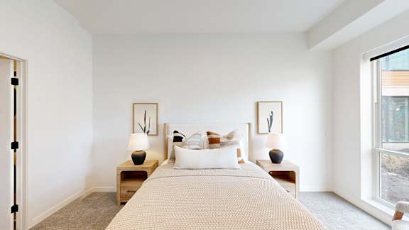 A bedroom with a large bed and two nightstands with lamps.
