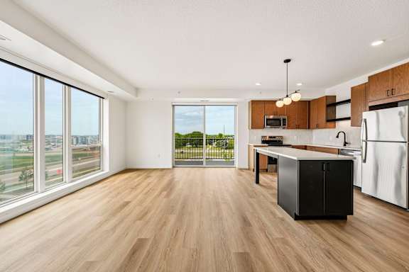 A kitchen with a black fridge and wooden floors.