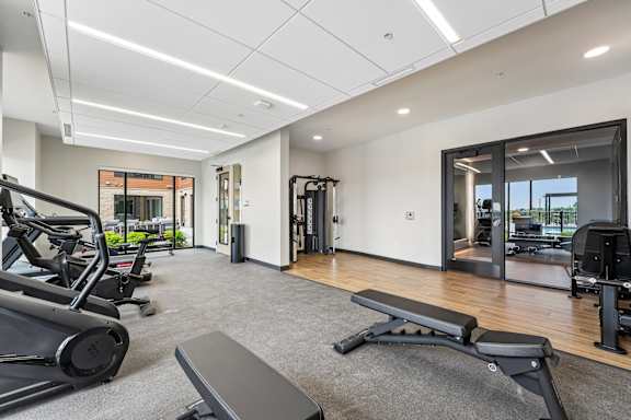 A gym with a variety of equipment including treadmills, weights, and exercise machines.