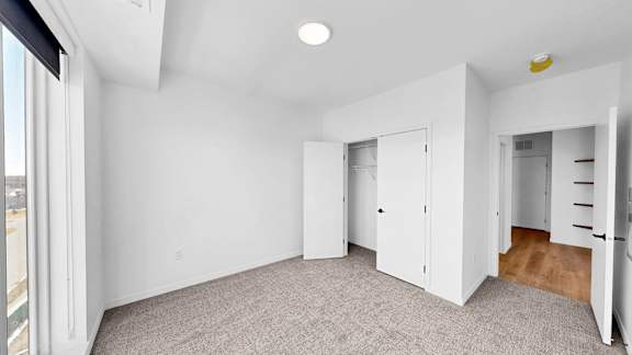 A white room with a grey carpet and a window.