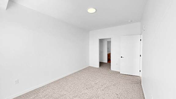 A room with a carpeted floor and a white door.