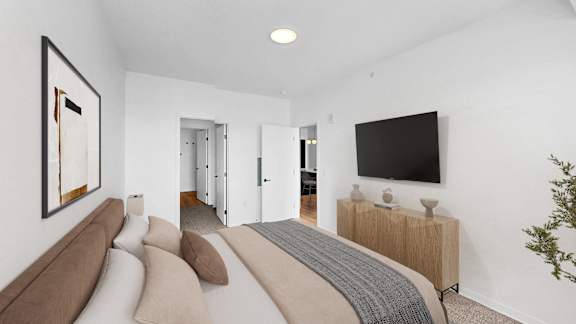 A modern bedroom with a large bed and a flat screen TV on the wall.