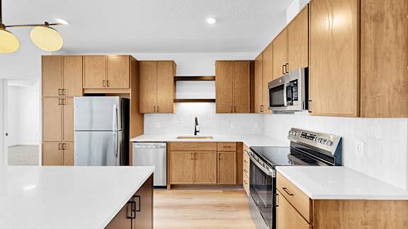 A modern kitchen with wooden cabinets and white countertops.