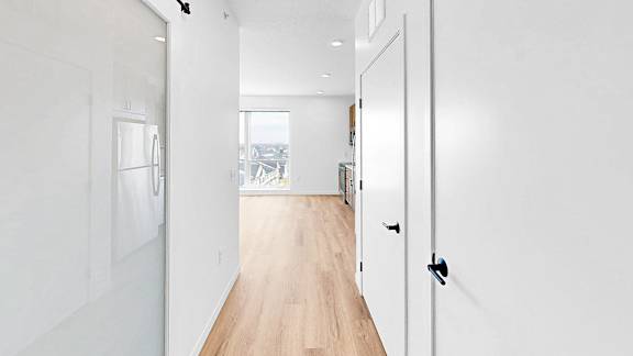 A long hallway with white walls and wood floors.