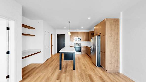 A modern kitchen with wooden floors and a central island.