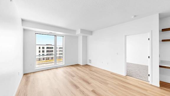A large empty room with a view of a building outside the window.