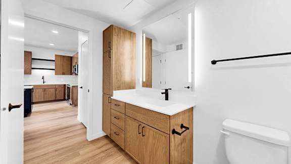 A bathroom with a white sink and wooden cabinets.
