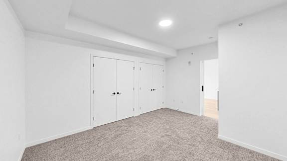 A room with white walls and a carpeted floor with four white doors.