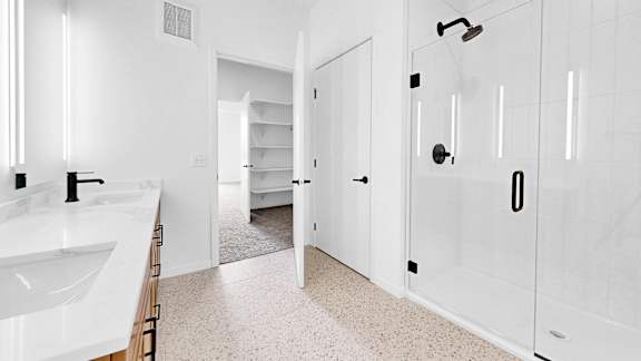 A white bathroom with a sink, mirror, and shower.