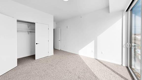 A spacious, empty room with a carpeted floor and white walls.