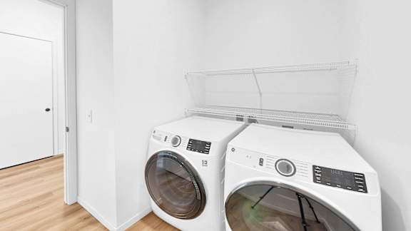 Two white front load washing machines in a laundry room.