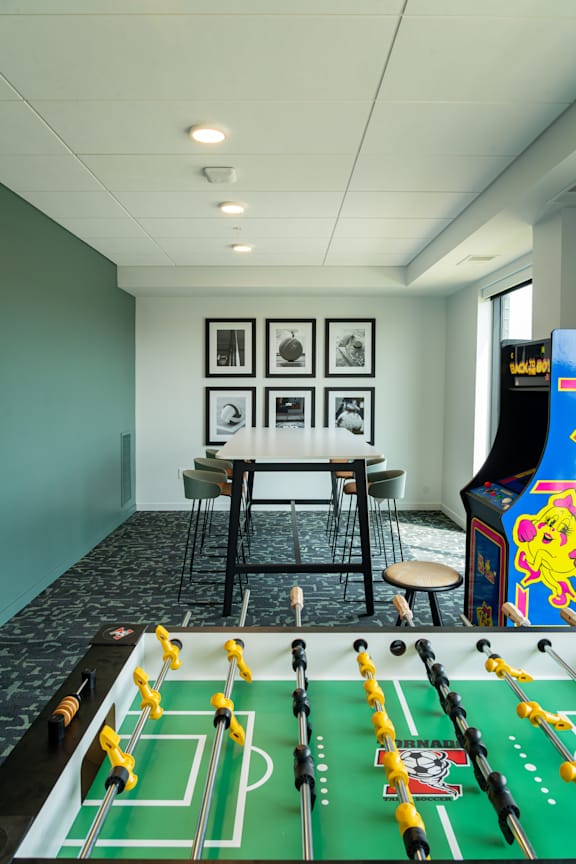 A foosball table is in the middle of a room with a bar and chairs.