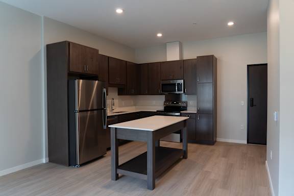 A kitchen with a refrigerator, microwave, oven, and sink.