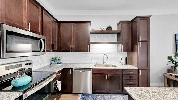A kitchen with brown cabinets and a white backsplash.