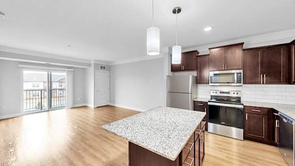 A kitchen with a granite countertop and stainless steel appliances.