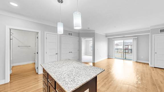 A spacious kitchen with a granite countertop and white cabinets.