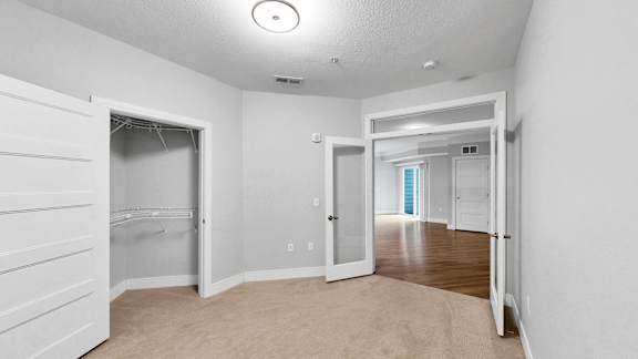 A white room with a carpeted floor and a doorway leading to another room.