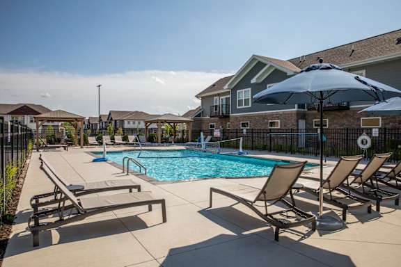 A pool surrounded by chairs and umbrellas.at The Edison at Spirit, Lakeville, MN 55044
