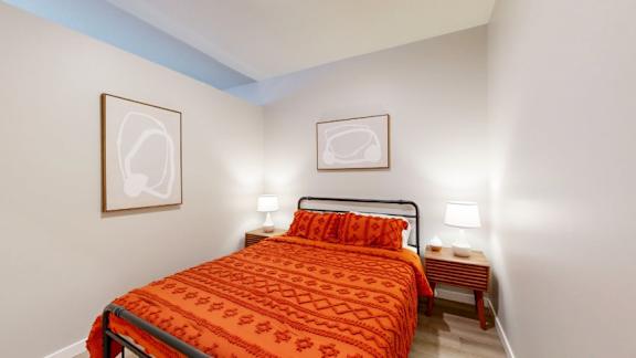 A bedroom with a bed, two lamps, and two pictures on the wall.