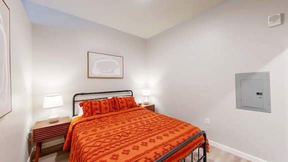 A bedroom with a bed, nightstands, and a picture on the wall.