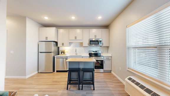 A kitchen with a refrigerator, microwave, oven, and sink.