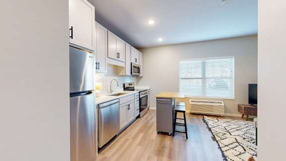 A modern kitchen with stainless steel appliances and wooden flooring.
