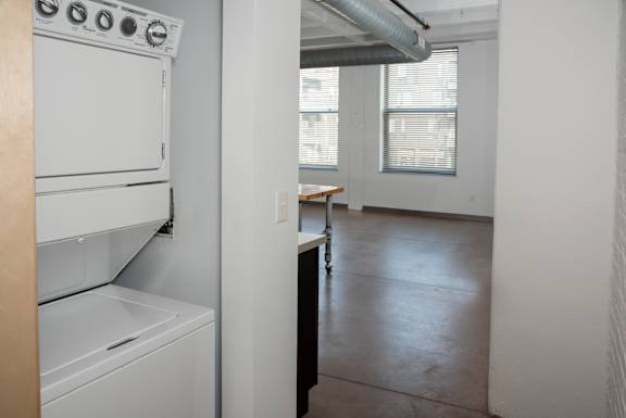 A white dishwasher is in a kitchen with a white wall.