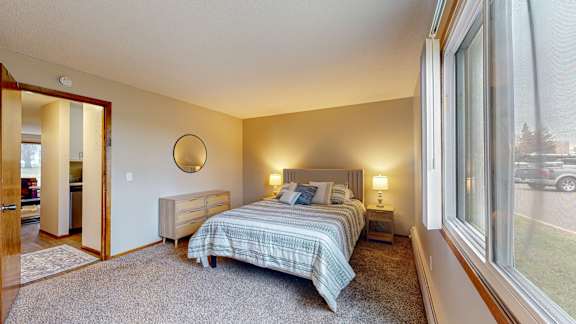 A bedroom with a bed, nightstand, and window.