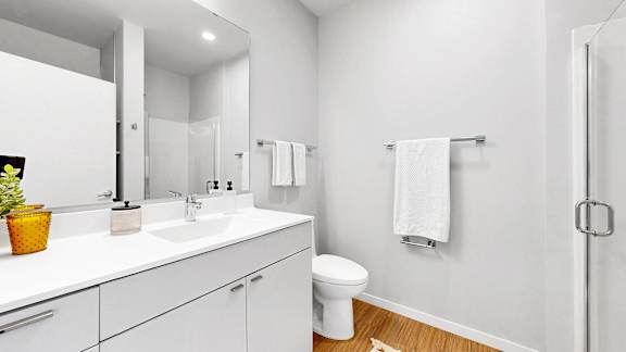 A white bathroom with a toilet, sink, and mirror.