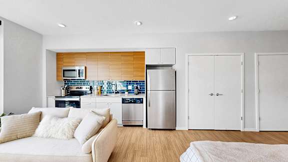 A modern kitchen with a white couch and wooden accents.