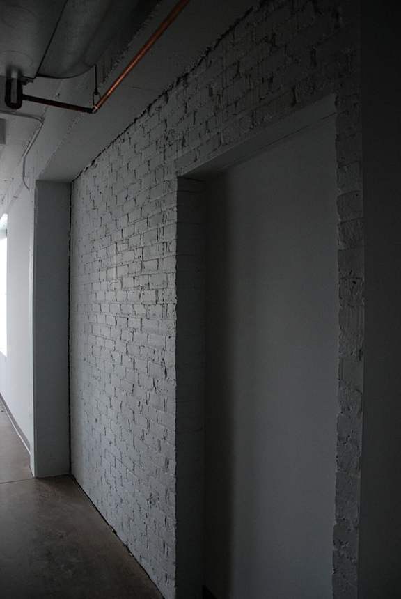 A white brick wall with a door and a window.