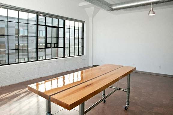 A long wooden table with metal legs sits in a room with a window.