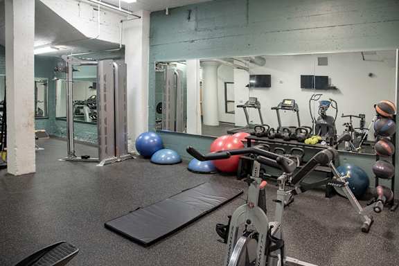 A gym with a variety of equipment including a stationary bike, a rowing machine, and a bench.at Gurley Lofts, Minneapolis
