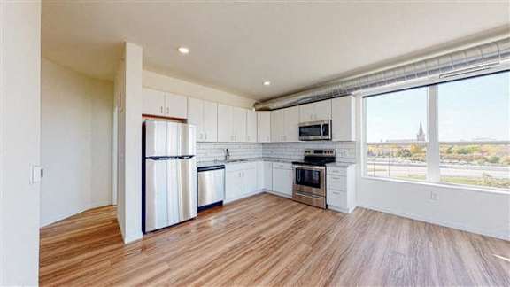 A kitchen with white cabinets and stainless steel appliances at The Bessemer at Seward Commons Apartments, Minneapolis, MN,  55404