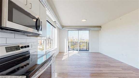 A kitchen with a black stove top oven and a black microwave above it at The Bessemer at Seward Commons Apartments, Minnesota, 55404