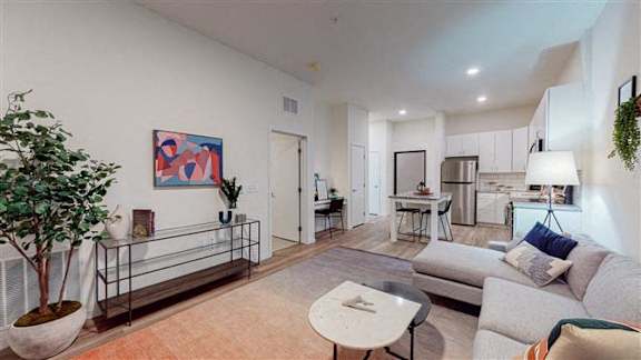 A living room with a couch, a table, and a painting on the wall at The Bessemer at Seward Commons Apartments, Minneapolis, Minnesota