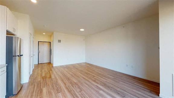 A kitchen with a refrigerator and wooden floors at The Bessemer at Seward Commons Apartments, Minneapolis, MN,  55404