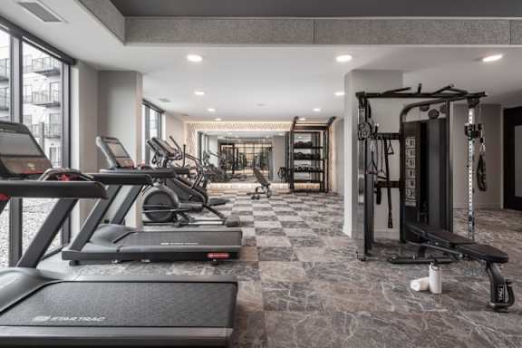A gym with treadmills, weights, and a bench.